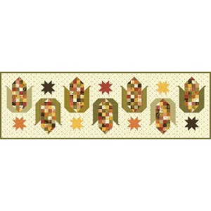 May include: A rectangular quilted table runner with a repeating pattern of corn on the cob and star shapes. The corn is made of patchwork squares in shades of brown, orange, and green. The background is a light beige with small dots.