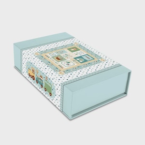 May include: A light blue gift box with a decorative lid featuring a patchwork design with various illustrations, including a train, rainbow, and other cute images. The box has a matching light blue base.