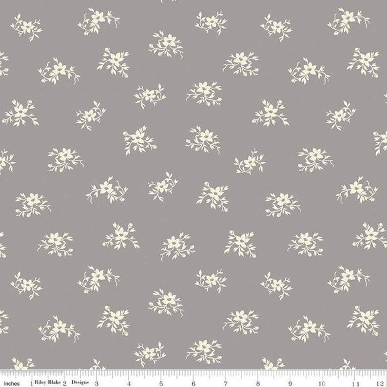 May include: A gray fabric with a white floral pattern. The flowers are small and delicate, and they are arranged in a repeating pattern.