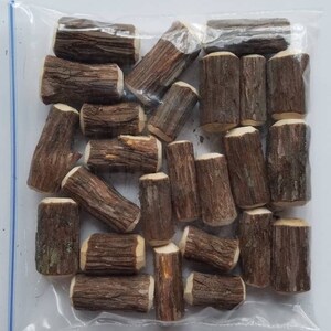 May include: A clear plastic bag filled with small, brown wooden logs. The logs are approximately 1-2 inches in length and have a natural, rustic appearance.
