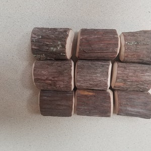 May include: Nine small, brown wooden logs with a rough, bark-like texture. The logs are arranged in three rows of three, with the top row slightly offset from the bottom row.