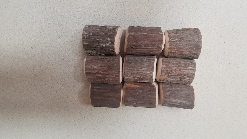 May include: Nine small, brown wooden logs with a rough, bark-like texture. The logs are arranged in three rows of three, with the top row slightly offset from the bottom row.