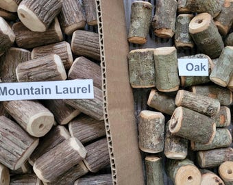 May include: Two boxes filled with different types of wood pieces. The box on the left is labeled "Mountain Laurel" and the box on the right is labeled "Oak".