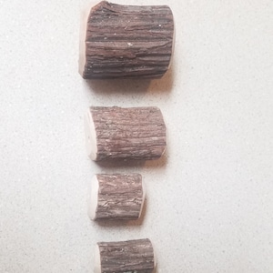 May include: Four wooden log slices of varying sizes, arranged vertically from largest to smallest. The logs are brown with a natural bark texture.