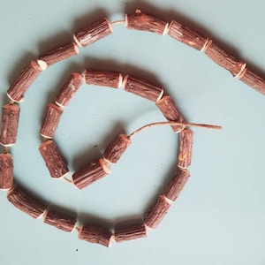 May include: A brown wooden garland with white accents, made of small wooden pieces strung together with twine.