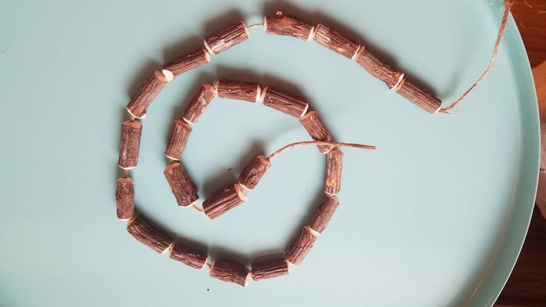 May include: A brown wooden garland with white accents, made of small wooden pieces strung together with twine.