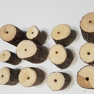 May include: A collection of 12 wooden rounds with holes drilled through the center. The rounds are various sizes and have a natural wood finish.