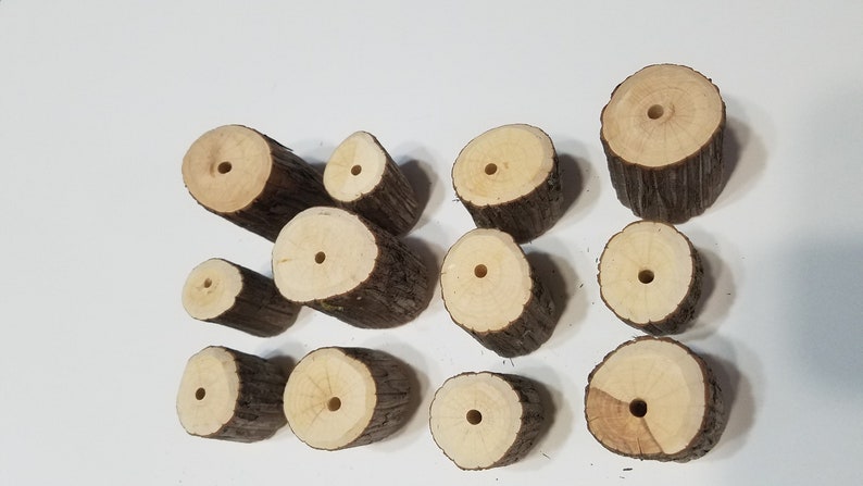 May include: A collection of 12 wooden rounds with holes drilled through the center. The rounds are various sizes and have a natural wood finish.