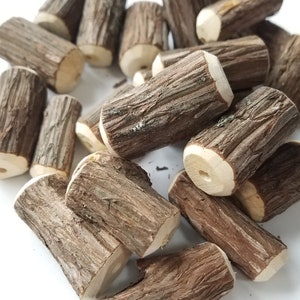 May include: A pile of small, brown, wooden logs with a rough, natural texture. The logs are arranged in a random pattern, with some of them stacked on top of each other.
