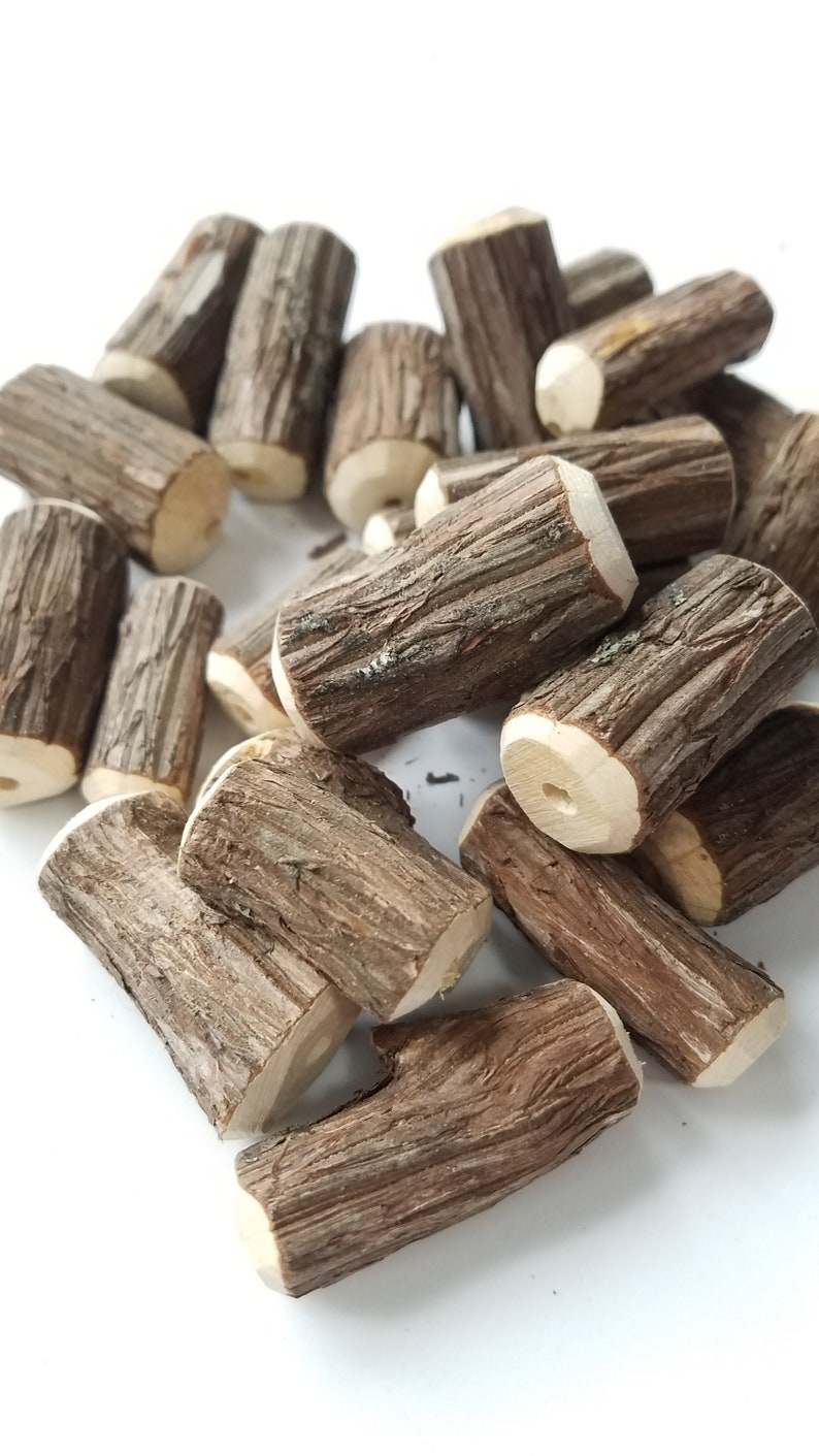 May include: A pile of small, brown, wooden logs with a rough, natural texture. The logs are arranged in a random pattern, with some of them stacked on top of each other.