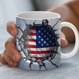 May include: White ceramic mug with a graphic of the American flag breaking through a cracked concrete wall.
