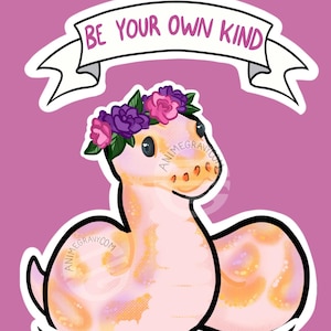 May include: A pink and orange snake with a flower crown, curled up in a circle. The snake is on a pink background with a white banner that says "Be your own kind of beautiful".