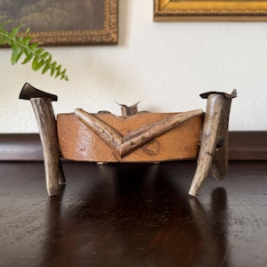 May include: A wooden bowl with a unique design, crafted from antlers and metal. The bowl is supported by four antler legs and has a rustic, natural look.