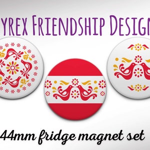 Könnte beinhalten: Set aus drei 44 mm Kühlschrankmagneten mit einem stilisierten Vogeldesign in Rot und Gelb. Die Magnete sind rund und haben einen weißen Hintergrund.