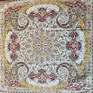 May include: A white rug with a detailed floral pattern in shades of red, yellow, and green. The rug has a central medallion with a repeating pattern of flowers and leaves.