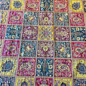 May include: A colorful quilt with a patchwork design featuring a variety of paisley patterns in shades of yellow, red, blue, and green.