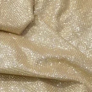 May include: Close-up of a gold fabric with a sparkly texture. The fabric has a subtle sheen and is ideal for crafting or sewing projects.