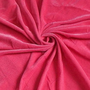 Puede incluir: Primer plano de una tela de terciopelo suave de color rosa. La tela está drapeada y doblada, mostrando su textura y caída.