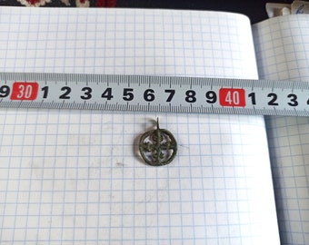 Könnte beinhalten: Ein kleiner, runder Bronzeanhänger mit einem Kreuzdesign. Der Anhänger hat einen Durchmesser von etwa 2,5 cm und eine Öse oben zum Aufhängen.