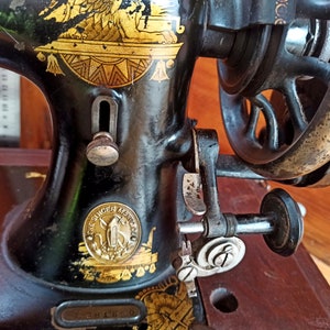 May include: A vintage black Singer sewing machine with gold accents and a decorative eagle design. The machine has a wooden base and a metal foot pedal.