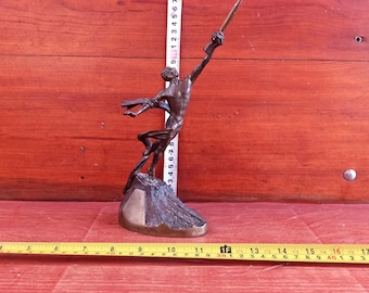 Könnte beinhalten: Eine Bronzeskulptur einer Person, die eine Lanze hält und auf einem felsigen Sockel steht. Die Skulptur ist etwa 18 cm hoch.