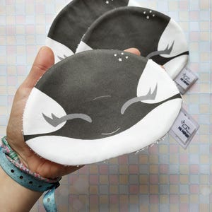 Puede incluir: Tres toallitas de tela grises y blancas con un diseño de ballena sonriente y el texto "dream big my warrior".