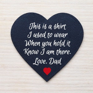 May include: A black heart-shaped plaque with white text that reads "This is a shirt I used to wear When you hold it Know I am there. Love, Dad". A small red heart is at the bottom of the plaque.