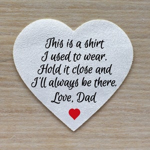 May include: White heart-shaped paper with the text "This is a shirt I used to wear. Hold it close and I'll always be there. Love, Dad" in black lettering. A small red heart is at the bottom of the paper.