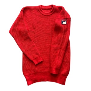 May include: Red knitted sweater with a white "F" logo on the left sleeve.
