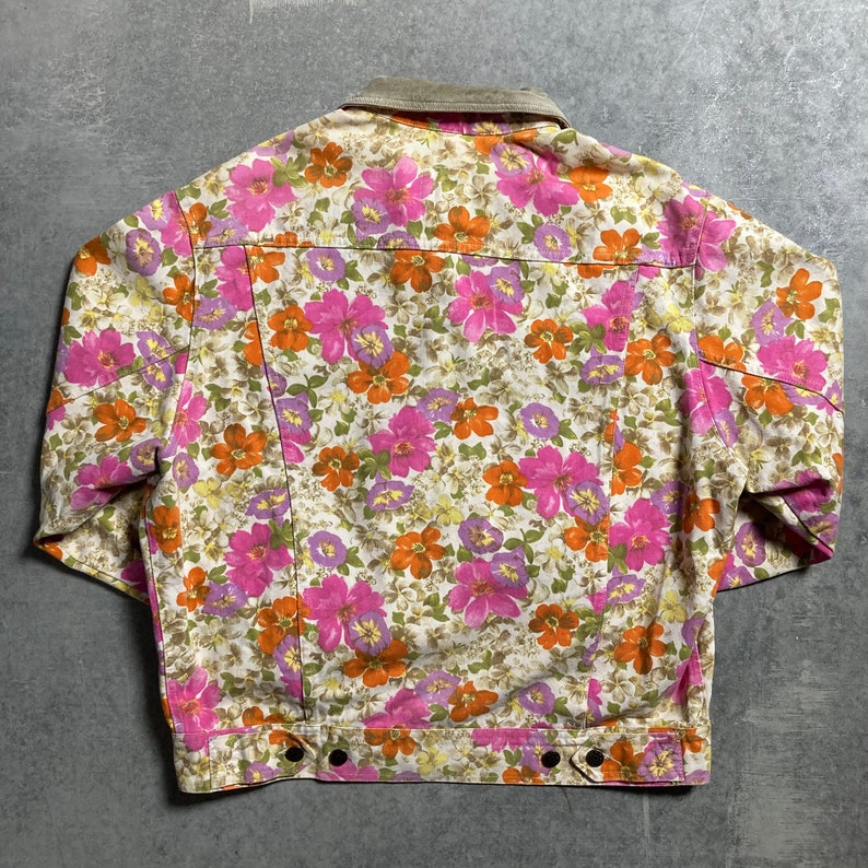 May include: A vintage floral print denim jacket with a corduroy collar. The jacket features a white background with pink, orange, and purple flowers.