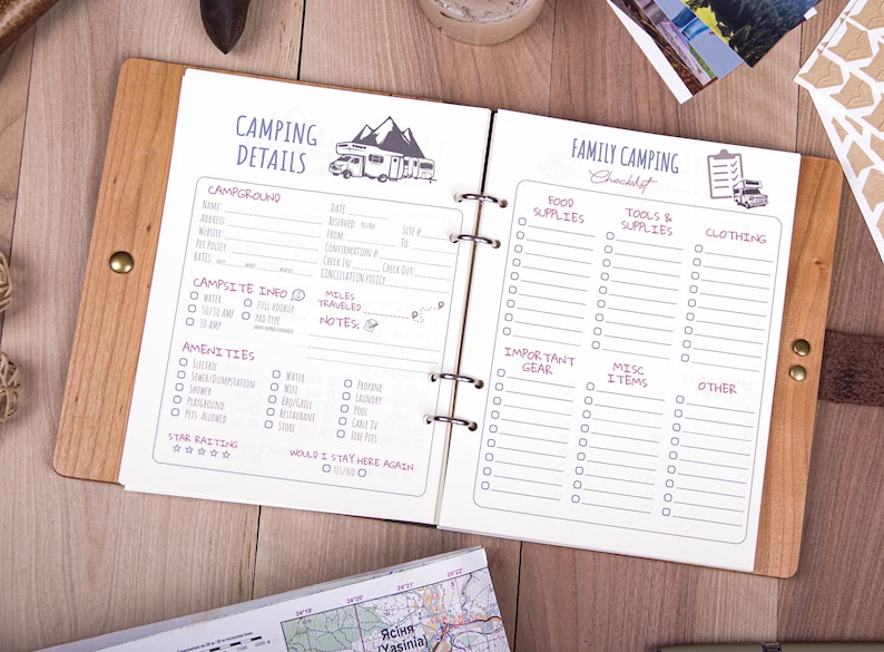 May include: A white camping checklist notebook with a brown wooden cover. The left page has a section for camping details, including campground name, address, amenities, and campsite information. The right page has a checklist for family camping, with sections for food supplies, tools and supplies, clothing, important gear, miscellaneous items, and other.