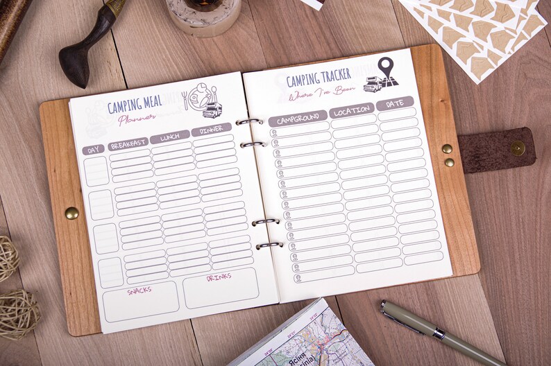 May include: A brown leather-bound journal with a white interior. The journal is divided into two sections: a camping meal planner and a camping tracker. The meal planner includes sections for breakfast, lunch, dinner, snacks, and drinks. The camping tracker includes sections for campground, location, and date.