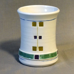 May include: White ceramic vase with a geometric design in green, yellow, and purple.