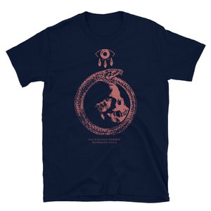 以下が含まれることがあります： 濃い青色のTシャツに、ピンク色の蛇の中に頭蓋骨が描かれたグラフィックがプリントされています。頭蓋骨の上には目と涙が滴り落ちています。グラフィックの下には「生命、死、再生のサイクル、魂の輪廻」というテキストが書かれています。