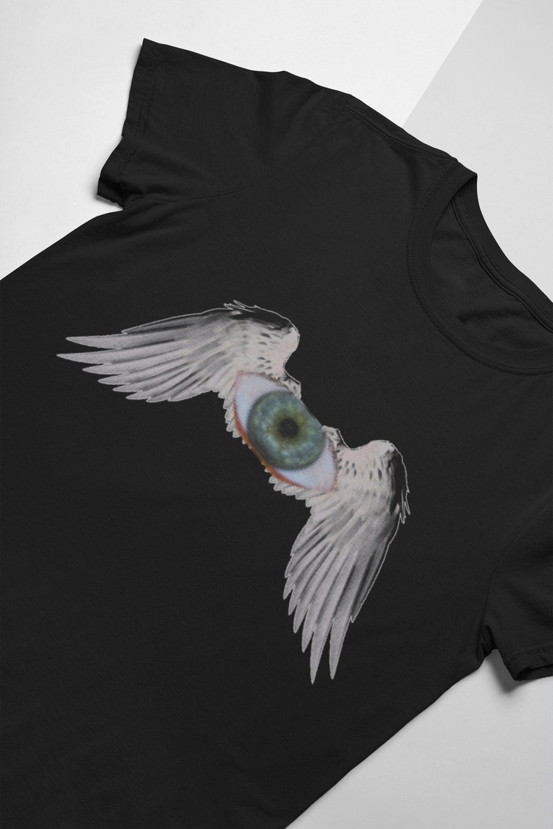 May include: Black t-shirt with a graphic of a large eye with wings. The eye is green and the wings are white.