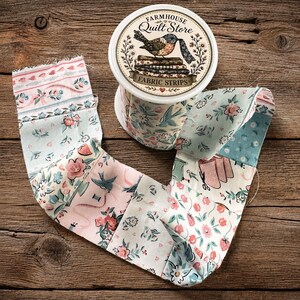 May include: A roll of fabric strips labelled Farmhouse Quilt Store with a bird illustration. The fabric features a light blue and pink floral pattern with small birds, sewing tools, and strawberries printed on the cotton material.