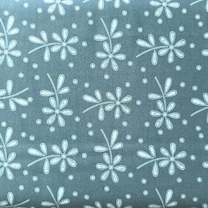May include: Close-up of a fabric featuring a repeating pattern of white floral and leaf designs on a muted teal background. The design includes small white dots scattered throughout.