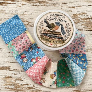 Puede incluir: Un recipiente redondo etiquetado como Farmhouse Quilt Store Fabric Strips con una ilustración de un pájaro, acompañado de una larga tira continua de cuadrados de tela variados con patrones florales, de lunares y de ositos en azul, rosa y verde.