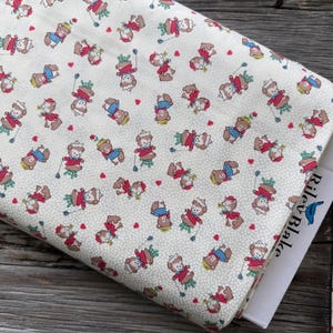 May include: Cream-colored fabric with a repeating pattern of cartoon bears in red, blue, and white outfits, holding golf clubs. Small red hearts are scattered throughout the design. A book with the text "Riley Blake" is visible.
