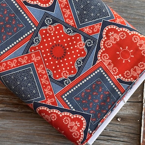 Könnte beinhalten: Gefalteter Stoff mit einem sich wiederholenden Muster aus roten, marineblauen und hellblauen Quadraten. Die Quadrate weisen Paisley-, Punkt- und Blumendesigns auf. Der Stoff ist wahrscheinlich Baumwolle, geeignet für Quilt- oder Bastelprojekte.