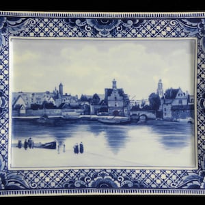 May include: A rectangular ceramic tray featuring a blue and white transferware pattern. The center depicts a riverside cityscape with boats and figures, while the border displays an intricate floral and geometric lattice design in blue.