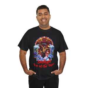 Peut inclure: T-shirt noir avec un graphisme coloré du film "Sinbad et l'Œil du Tigre". Le motif comprend un personnage central, un tigre et le titre du film en rouge. Le t-shirt est porté par une personne.