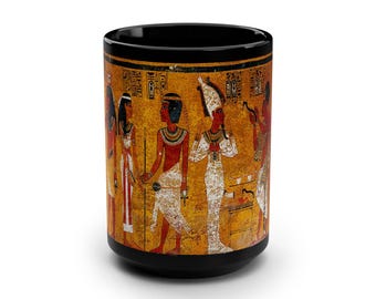 May include: Black ceramic mug with a colorful image of ancient Egyptian figures and hieroglyphics. The figures are depicted in a procession, wearing elaborate headdresses and clothing.