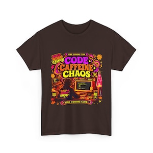 Op de afbeelding: Bruin t-shirt met een kleurrijk grafisch ontwerp. Het ontwerp bevat de woorden "CODE CAFFEINE CHAOS", een persoon achter een computer, een lavalamp en bloemmotieven. Het t-shirt is van de "Vibe Coding Club".