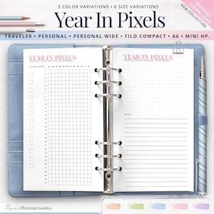 Puede incluir: Una doble página de planificador con una sección cuadriculada a la izquierda y una sección de notas con líneas a la derecha. Las páginas del planificador están tituladas "Year in Pixels" en texto rosa. El planificador está abierto en una carpeta azul.