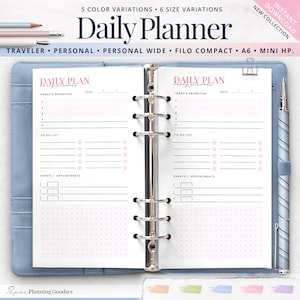 Könnte beinhalten: Ein blauer Planer mit dem Wortlaut "Daily Planner" in Rosa. Der Planer ist geöffnet und zeigt linierte Seiten für die Tagesplanung mit Abschnitten für Prioritäten, To-Do-Listen und Termine. Ein Stift und ein rosa Lederetui sind sichtbar.