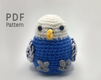 May include: Crochet pattern for a blue and white amigurumi parakeet. The pattern includes instructions for making the bird's body, head, beak, and feet.