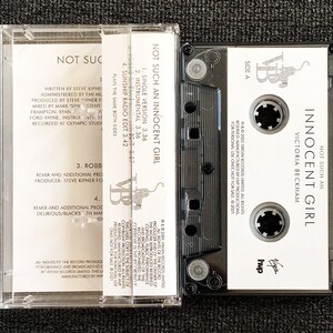 May include: A clear cassette tape case with a black cassette inside. The cassette label reads "NOT SUCH AN INNOCENT GIRL" by Victoria Beckham. The case also displays the track listing and production credits.