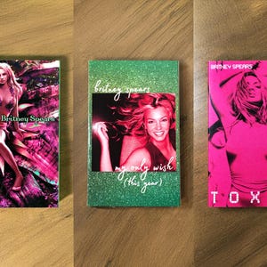 May include: Three Britney Spears themed items. The first features a pink and purple image of Britney with the text "Britney Spears". The second is green with a photo of Britney and the text "my only wish (this year)". The third is pink with the word "TOXIC".