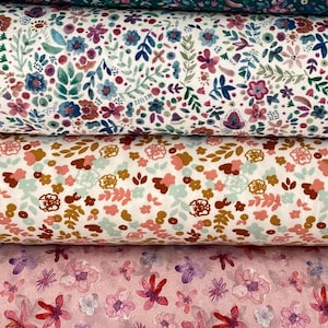 May include: Five different fabric swatches with floral patterns. The top swatch is a dark teal fabric with a small floral pattern. The second swatch is a white fabric with a small floral pattern. The third swatch is a light pink fabric with a small floral pattern. The fourth swatch is a light pink fabric with a larger floral pattern. The bottom swatch is a light beige fabric with a small floral pattern.
